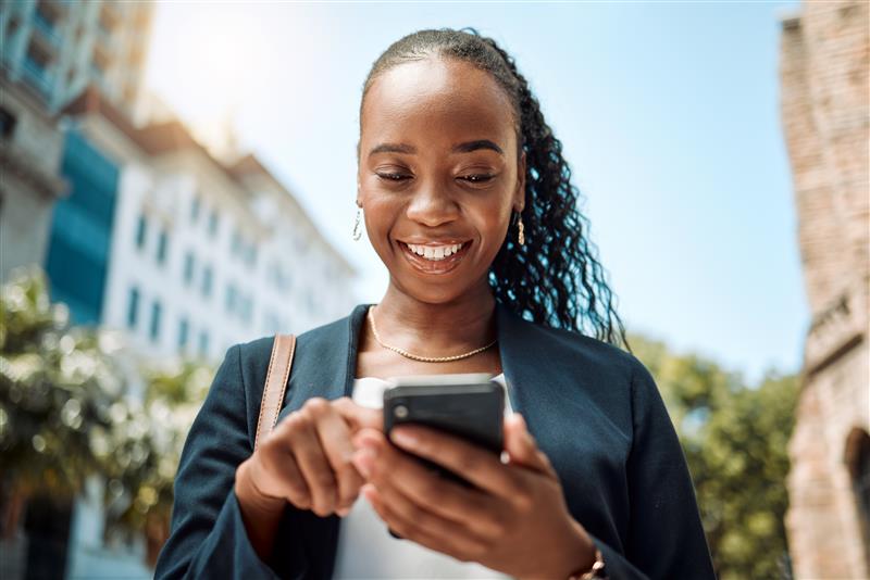 A woman looking and smiling at her phone as she scrolls through her feed.